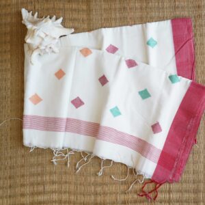 A pure cotton handwoven red and white Bengali Jamdani saree laid out on a mat, perfect for Durga Puja or Saraswati Puja